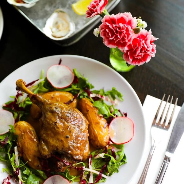 Duck confit with roasted potatoes, fresh greens, radishes, and a side of oysters.